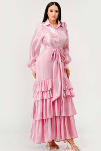 Pink Tiered Ruffle Maxi Dress with Belt: A long pink dress featuring a button-up front, tiered ruffle skirt, and a matching fabric belt at the waist. The dress has long, puffed sleeves and a collared neckline. Rêve Dorés