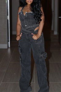 Model showcasing a trendy black denim jumpsuit with a strapless design, featuring a belted waist and utility-style pockets for a chic, urban look. The straight-leg fit and rugged detailing make it a perfect statement piece for casual outings or streetwear-inspired ensembles