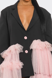 Oversized Tulle Blazer Dress Black and Pink
Model wearing a bold and avant-garde blazer dress in black, featuring a plunging neckline, oversized silhouette, and pastel pink ruffled tulle accents cascading asymmetrically. A statement piece blending edgy tailoring with whimsical femininity, styled with clear heels for a modern touch. - Rêve Dorés