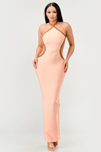 Peaches and Cream Infinity Gown Bandage dress Model wearing a sleek peach maxi dress featuring a halter neckline with contrasting brown trim accents that outline the curves, creating a sophisticated and contemporary silhouette. Perfect for formal events or evening occasions - Rêves Dorés